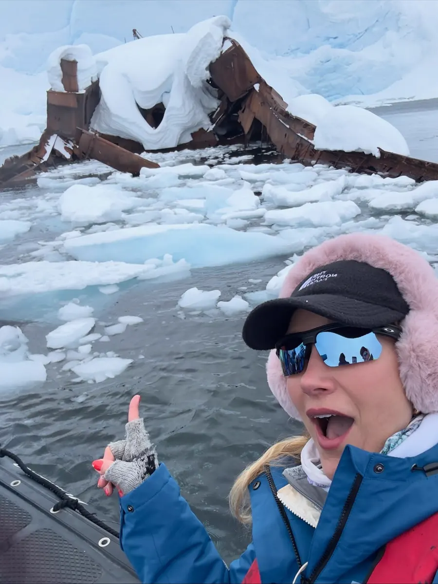 Selfie de Gabriela Morais durante expedição de barco na Antártica, entre blocos de gelo.